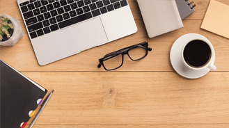 office desk with keyboard, potted plant, glasses, coffee, and notepad