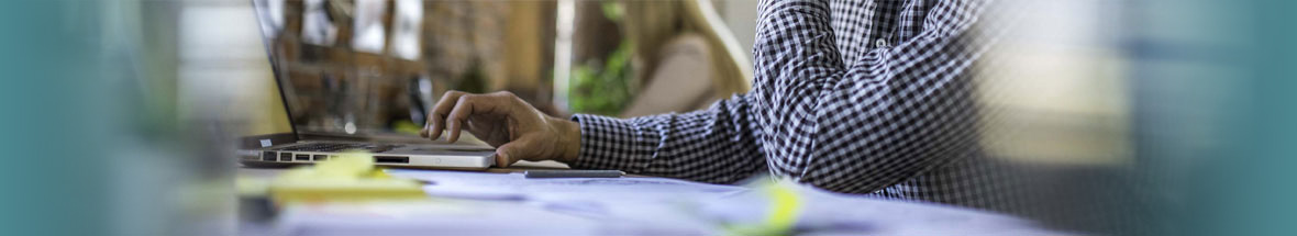 man using a laptop while surrounded by business papers